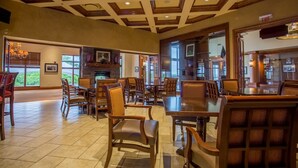 A spacious indoor area with multiple seating arrangements, a fireplace, and large windows offering views of the outdoors. - Birdie's Paradise 2 Bedroom Villa by RedAwning (Branson)