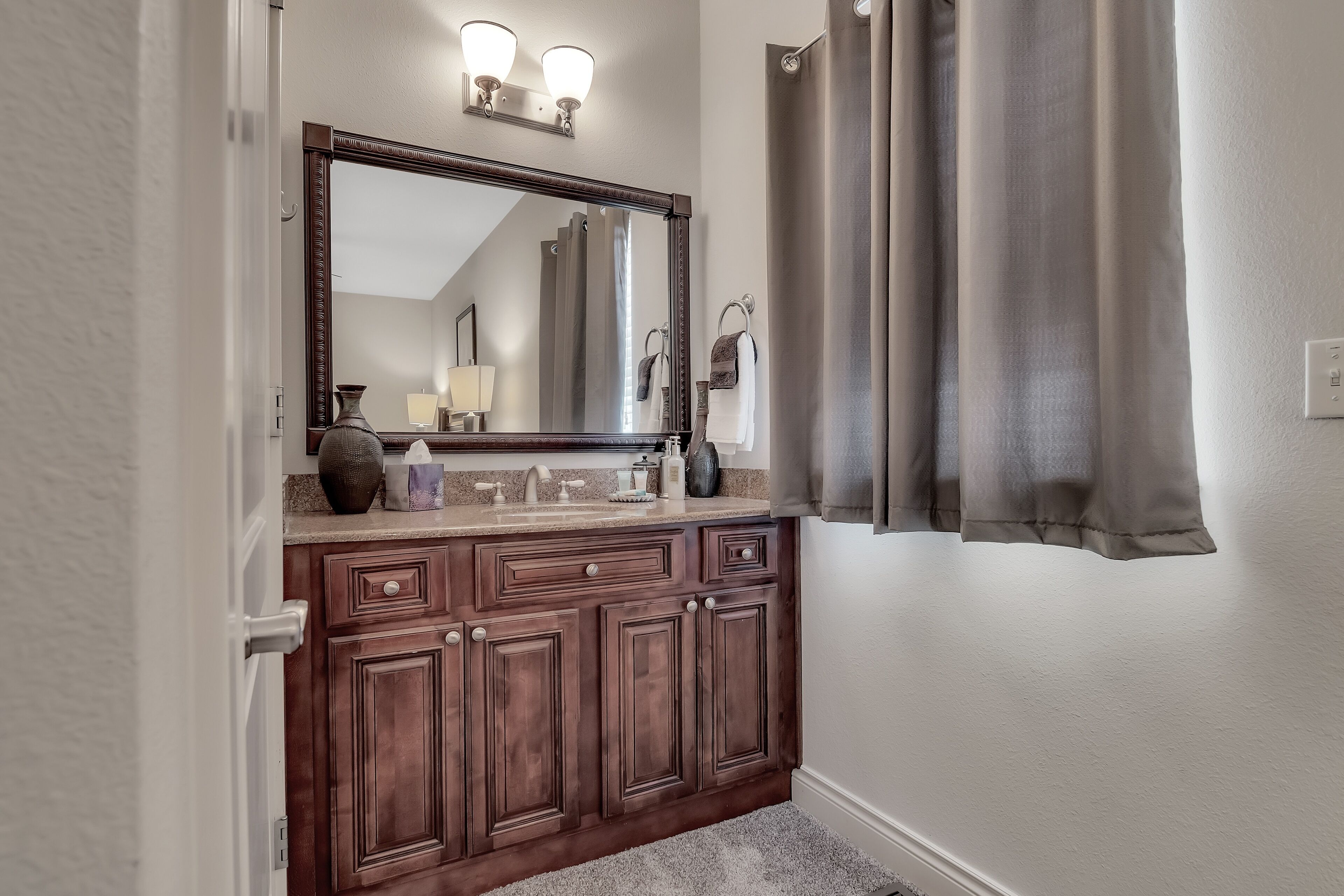 A bathroom with a wooden vanity, a large mirror, and a shower curtain.