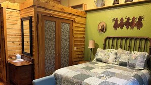 A wooden room with a bed, a chair, a nightstand, and a wardrobe. - Mountain Peaks Inn, GREEN MOUNTAIN SUITE, Downtown Hill City (Hill City)