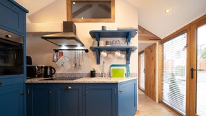 A modern kitchen with blue cabinetry, a built-in oven, and a large island with a sink. - Charming countryside cottage for couples with private hot tub and communal games room. (Barnstaple)