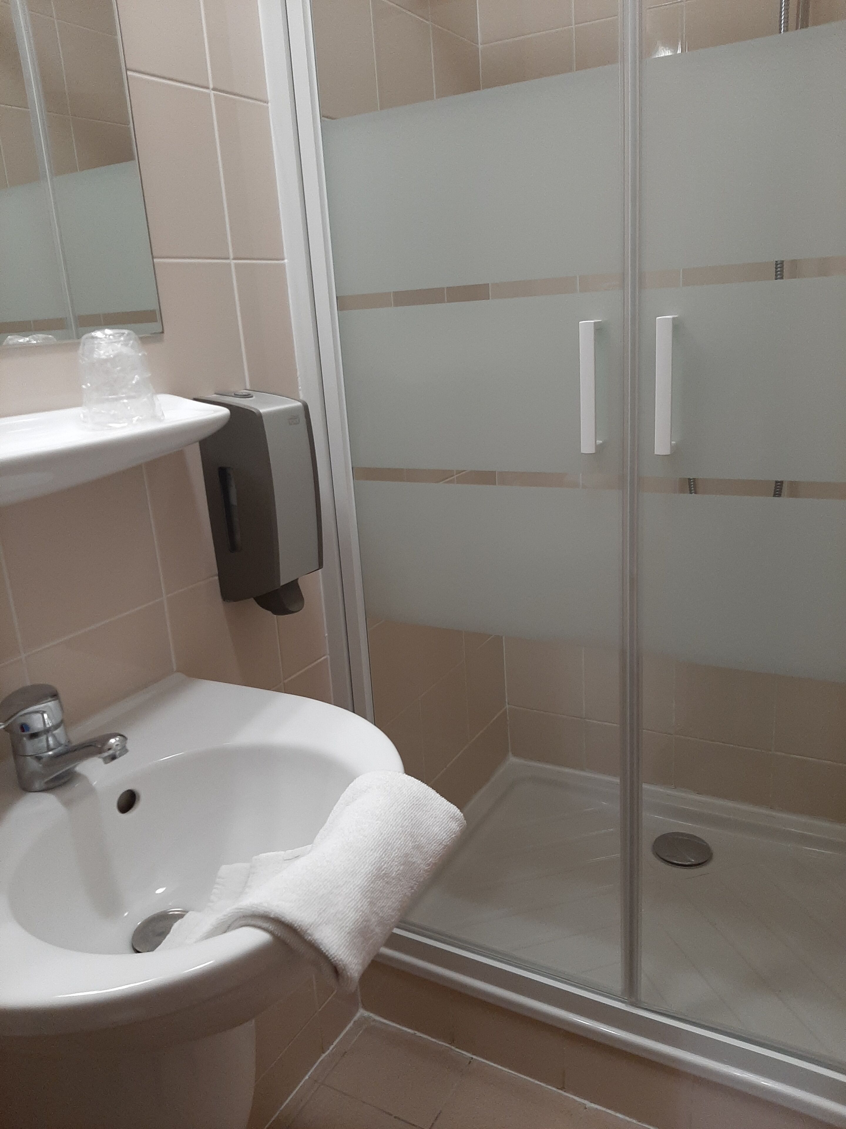 A bathroom with a sink, mirror, and a glass shower enclosure.
