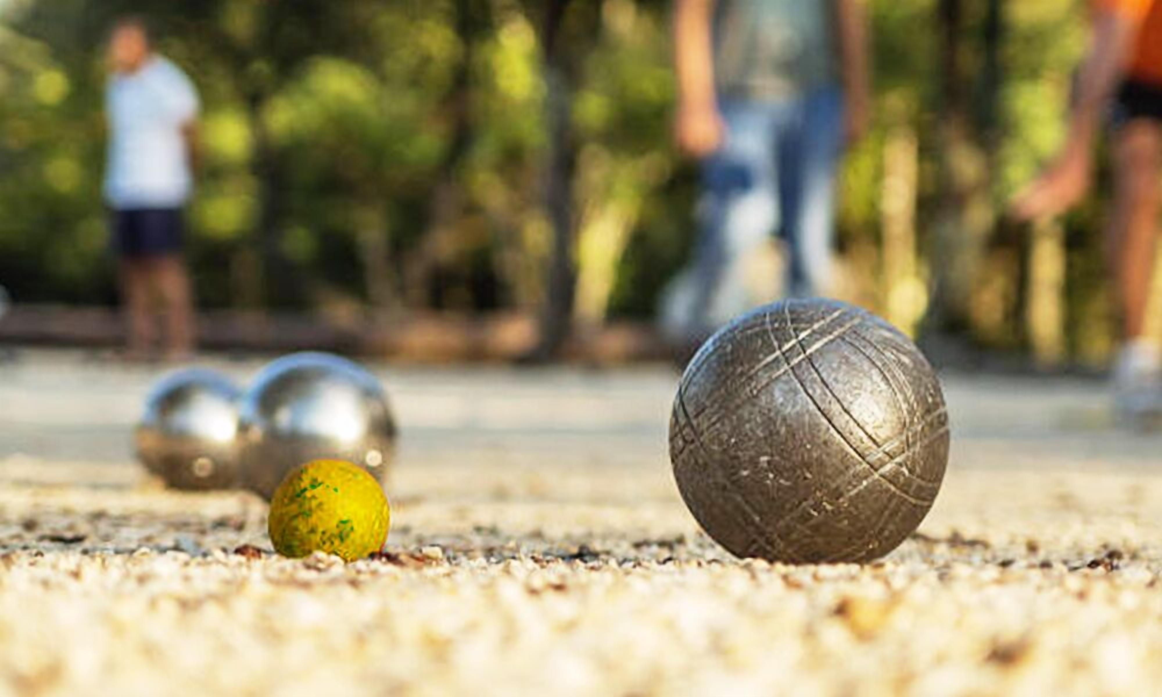 A close-up of a croquet ball on a sandy surface with other balls in the background.