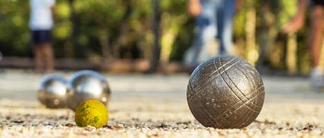Primer plano de una bola de croquet sobre una superficie arenosa, con otras bolas desenfocadas al fondo.