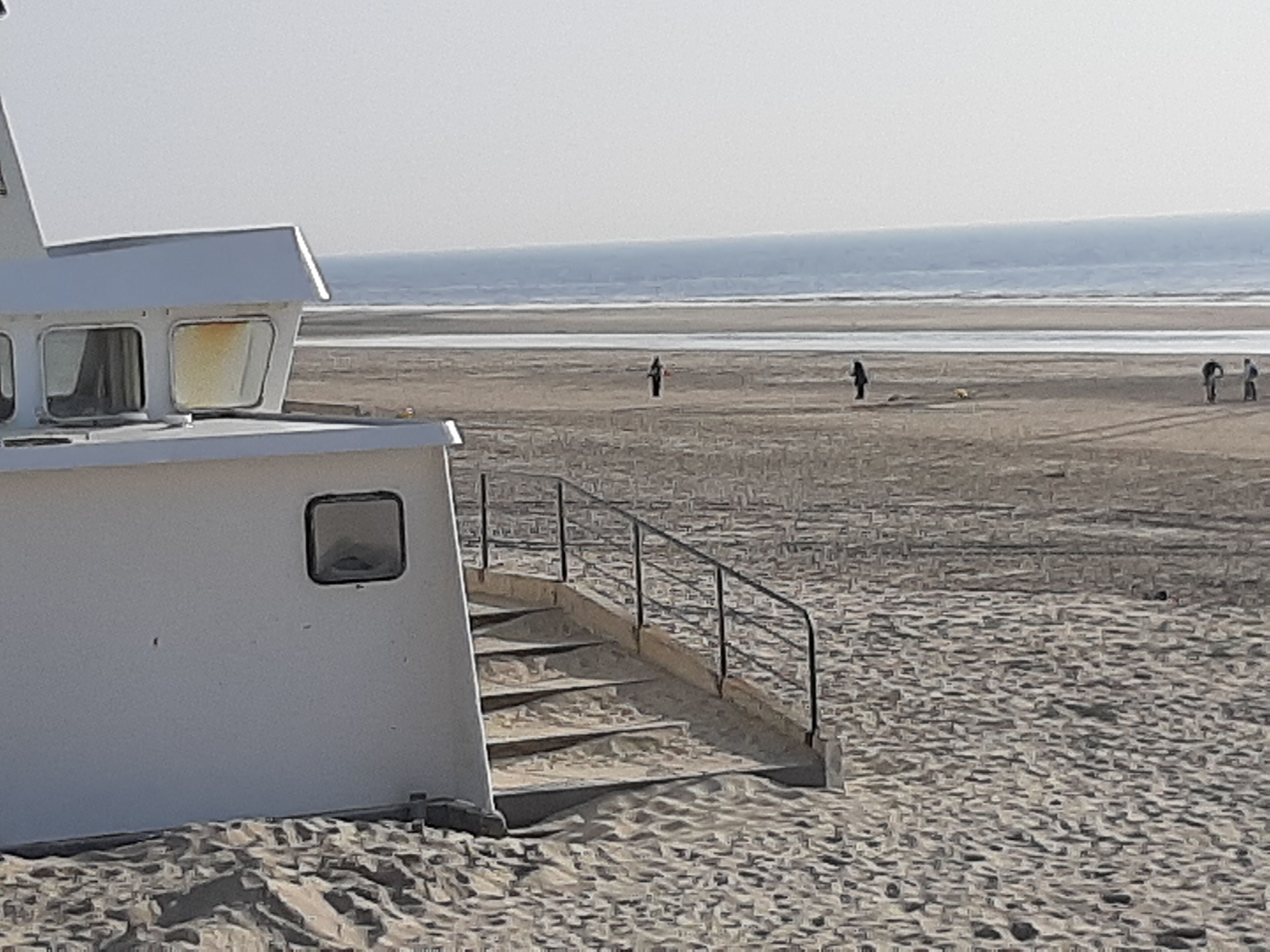 Ein weißes Gebäude mit einer Treppe, die zum Strand führt.