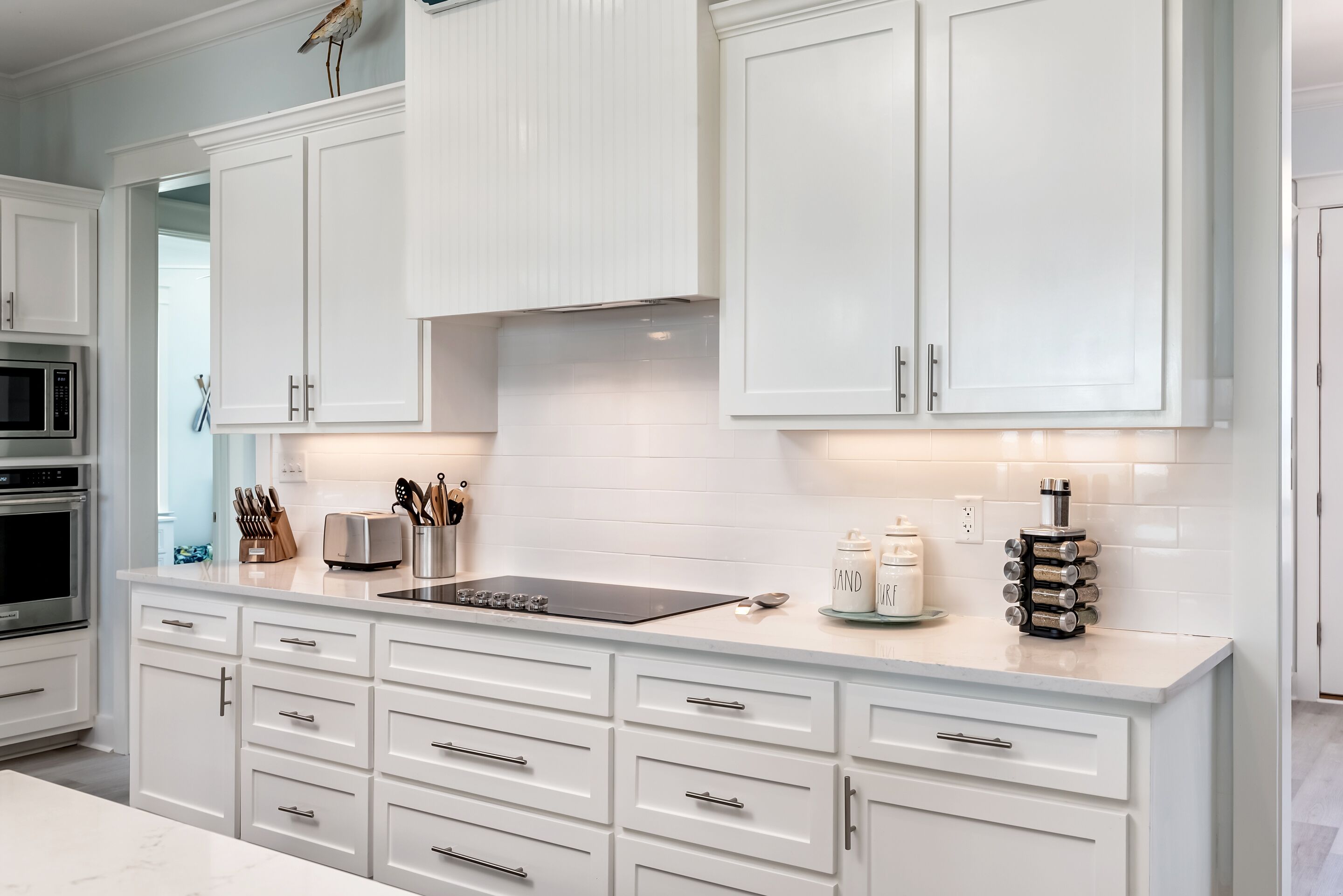 A modern kitchen with white cabinetry, a built-in microwave, and a stainless steel oven.