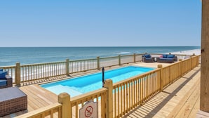 Un pontile in legno con piscina e vista sulla spiaggia.