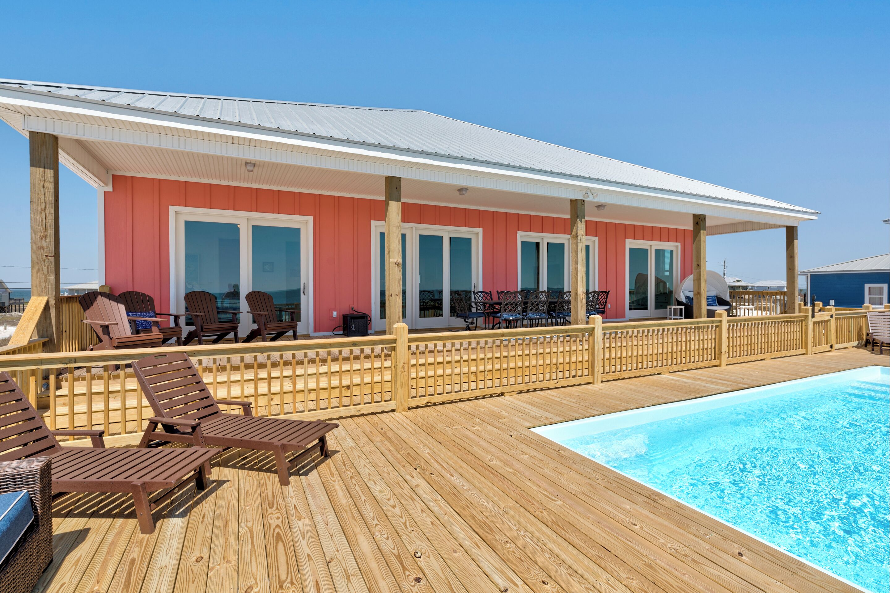 Een houten terras met lounge stoelen en een zwembad.