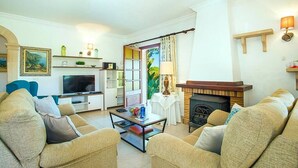 A living room with a television, sofa, coffee table, and fireplace. - Villa Geranios, country house a few minutes driving from Pollensa (Pollença)