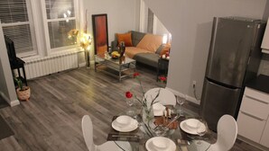 A dining area with a glass table set for four, surrounded by a kitchen with a refrigerator and cabinets.