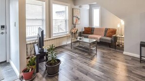 A living room with a sofa, coffee table, and potted plants.