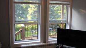 A room with two windows overlooking a deck with outdoor furniture.