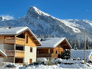 Een houten chalet met balkon, omringd door met sneeuw bedekte bomen en bergen.
