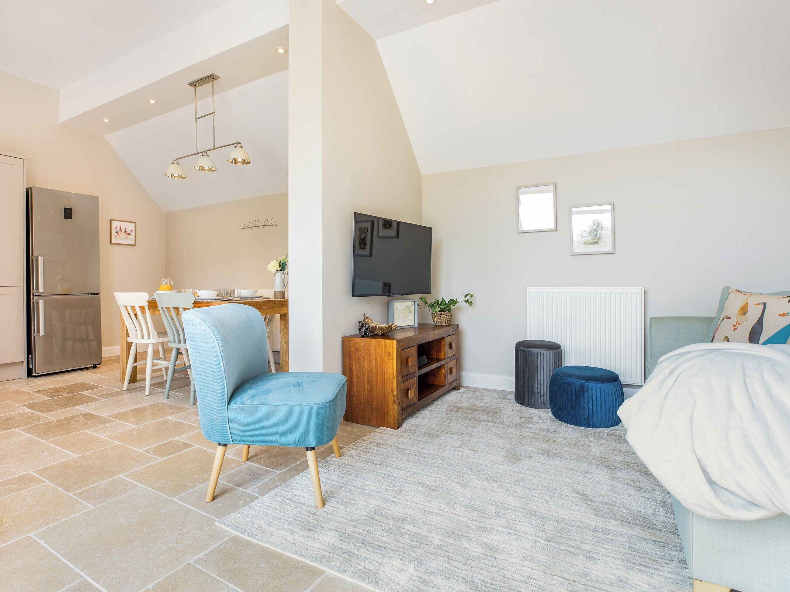 A modern living room with a sofa, a coffee table, a TV, and a dining area with chairs and a table.