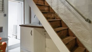 A staircase with wooden steps and a metal handrail, leading to a white door.