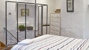 A bedroom with a bed, a metal partition, a dresser, and a framed picture on the wall.