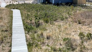 Une maison située en bord de mer, dotée d’une terrasse en bois et offrant une vue sur l’océan.