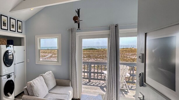 Un salon avec un canapé, une table et une vue sur la plage, grâce à de grandes fenêtres.
