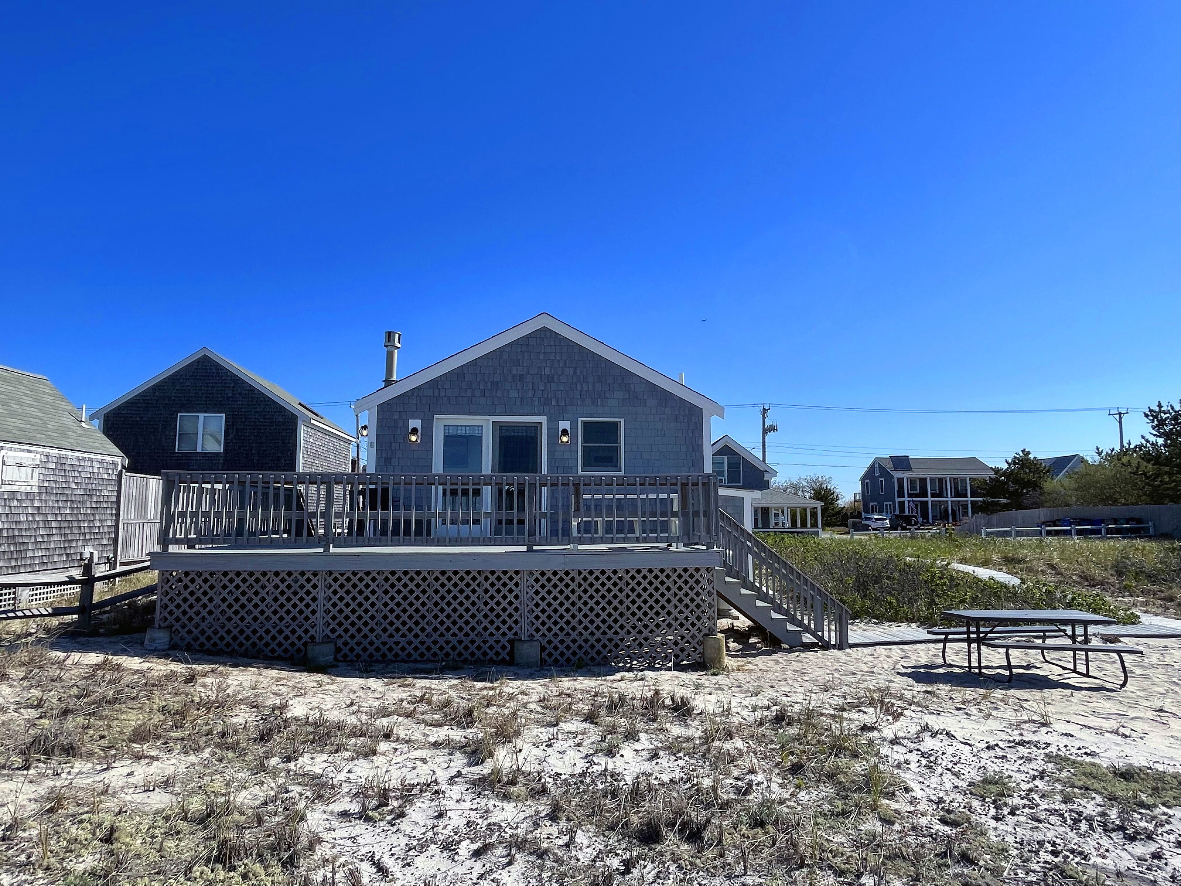 A beach house with a wooden deck and a small staircase leading to the entrance.