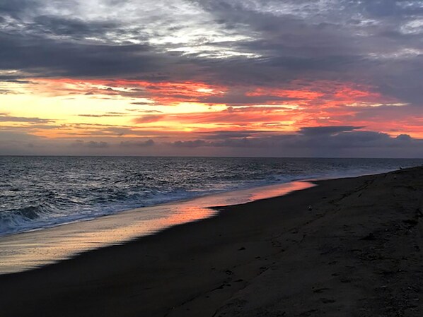 A beach with a sunset over the ocean.