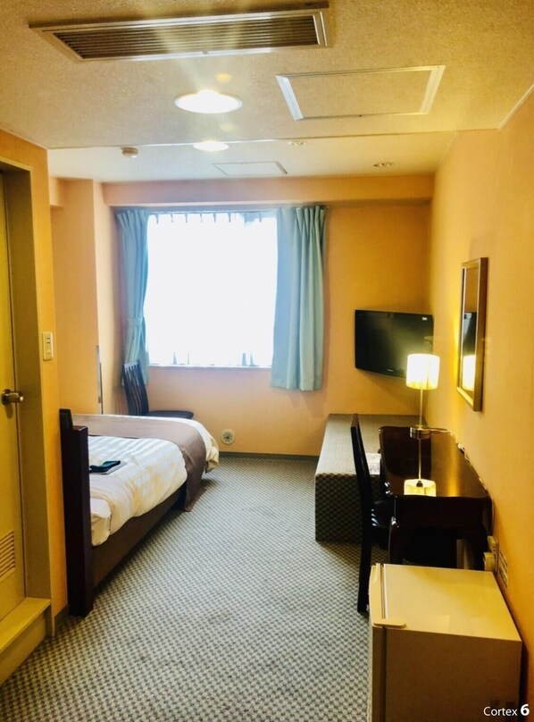 Habitación de hotel con dos camas, un escritorio, una silla, un televisor de pantalla plana, una lámpara y una ventana con cortinas.