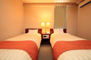 Two single beds with matching headboards and footboards, each with white linens and a red accent, are situated in this cozy space.