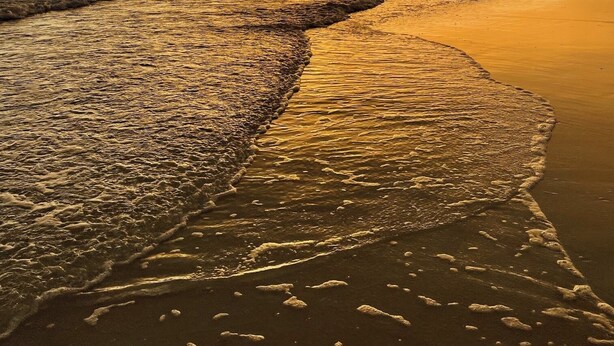 Une plage avec des vagues au coucher du soleil.