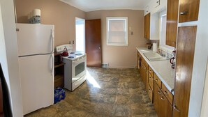 A kitchen with a refrigerator, microwave, stove, and wooden cabinets. - Sportsman's Country Lodge: The Fish House (Webster)