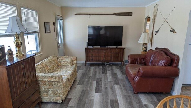 A living room with a TV, two sofas, a wooden cabinet, and a patterned armchair. - Sportsman's Country Lodge: The Fish House (Webster)
