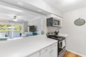 A kitchen with a stove, oven, microwave, and a clock on the wall. - Water View - optional BIKES - Walk 2 Pier Village (St. Simons Island)