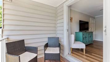 A balcony with wicker furniture, a television, and a teal cabinet in the background.