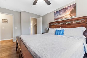 A bedroom with a large bed, wooden headboard, a painting on the wall, and a door leading to a closet. - Water View - optional BIKES - Walk 2 Pier Village (St. Simons Island)