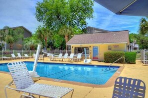A swimming pool with lounge chairs and a small building, surrounded by trees and fences. - Water View - optional BIKES - Walk 2 Pier Village (St. Simons Island)