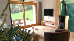 A living room with a TV, a fireplace, and a Christmas tree.