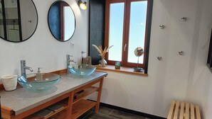 A bathroom with two glass sinks, a wooden vanity, a mirror, and a window with a view.