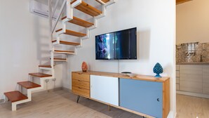 Un salon moderne avec un escalier, un téléviseur à écran plat et un meuble en bois.