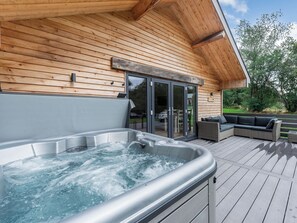 A wooden deck with a hot tub and outdoor seating.