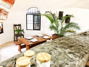 Enjoy meals in this cozy dining area with a wooden table for four, a potted plant, and a decorative window frame.