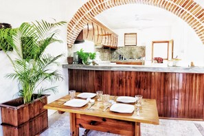 Enjoy meals in this cozy dining area with a table for four, surrounded by a rustic arched ceiling and a potted plant.