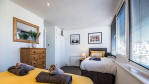 Ein Hotelzimmer mit zwei Betten, einem Schminktisch, einem Spiegel und einem Fenster mit Jalousien.