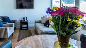 Ein Wohnzimmer mit einer Couch, einem Couchtisch und einem an der Wand befestigten Fernseher.