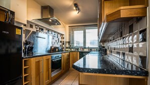 Eine moderne Küche mit einem schwarzen Kühlschrank, Holzschränken, einem Edelstahlherd und einer Marmorarbeitsplatte.