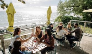 A group of people seated at an outdoor table with a view of the ocean.