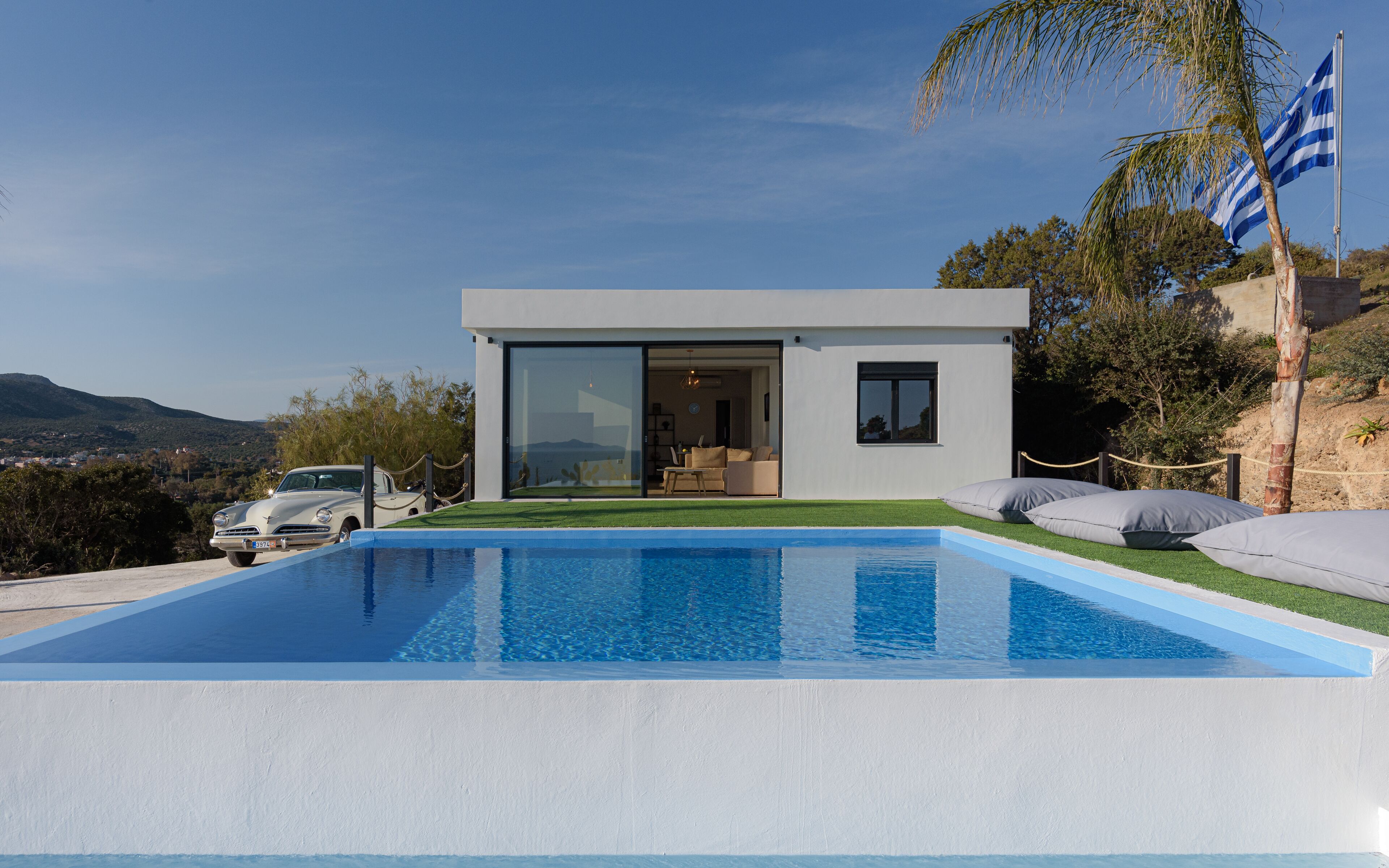 A modern house with a swimming pool, a car, and a flag.