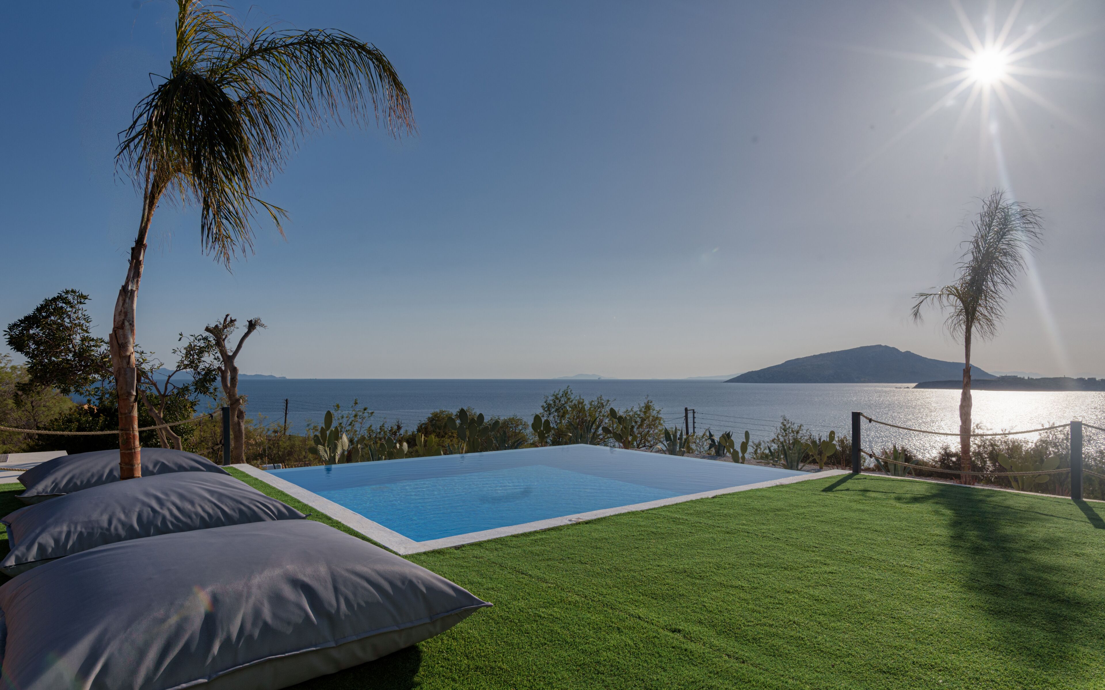 Une piscine avec vue sur la mer et une montagne qui se profile à l’horizon.