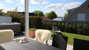 En terrasse med jacuzzi, siddepladser og udsigt til en sø.