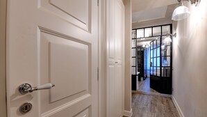 A hallway with a white door, wooden flooring, and a view into a room with a black and white color scheme. - DesenzanoLoft : La Vite Luxury Appartment 1 (Desenzano del Garda)