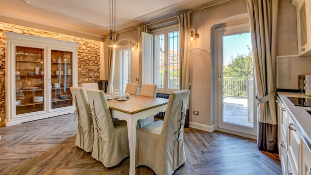 A dining area with a wooden table and chairs, a stone wall, and a view of the outdoors. - DesenzanoLoft : La Vite Luxury Appartment 1 (Desenzano del Garda)