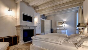 A bedroom with a large bed, a fireplace, a television, and a wardrobe. - DesenzanoLoft : La Vite Luxury Appartment 1 (Desenzano del Garda)