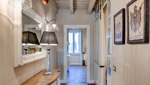 Ein Flur mit Holzboden, einem Spiegel, zwei Lampen und gerahmten Bildern an der Wand.