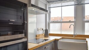 Une cuisine moderne dotée d’un four encastré, d’une hotte en acier inoxydable et d’une fenêtre offrant une vue sur le paysage urbain.